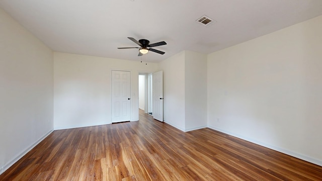 unfurnished room with ceiling fan, visible vents, baseboards, and wood finished floors