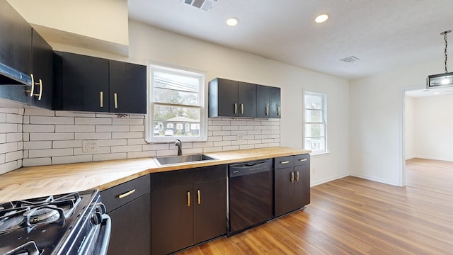 kitchen with a wealth of natural light, butcher block countertops, black appliances, a sink, and light wood finished floors