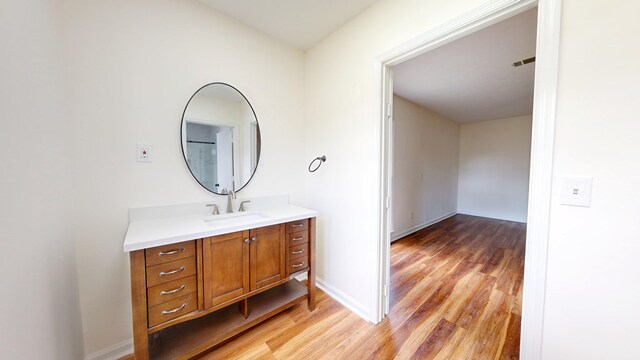 bathroom featuring vanity, visible vents, wood finished floors, and baseboards