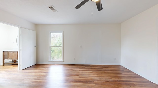 empty room featuring light wood finished floors, visible vents, baseboards, and ceiling fan