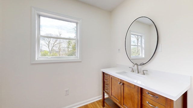 bathroom featuring plenty of natural light, vanity, baseboards, and wood finished floors