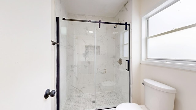 bathroom featuring a marble finish shower and toilet