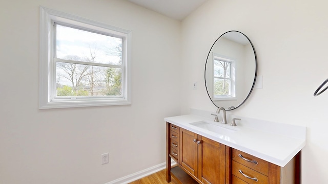 bathroom with a wealth of natural light, baseboards, wood finished floors, and vanity