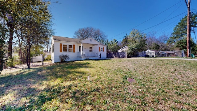 view of front of home featuring covered porch, a front lawn, and fence