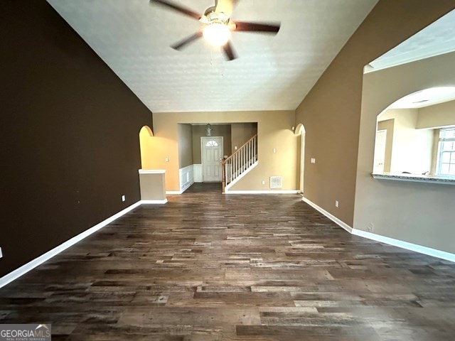 4254 Woodcove Dr, Snellville, GA 30039 - unfurnished living room featuring arched walkways, ceiling fan, wood finished floors, baseboards, and stairs