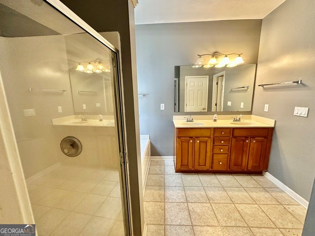 4254 Woodcove Dr, Snellville, GA 30039 - bathroom with baseboards, double vanity, a tub, and an enclosed shower