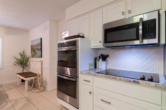 kitchen with white cabinets, light tile patterned flooring, tasteful backsplash, light stone countertops, and appliances with stainless steel finishes