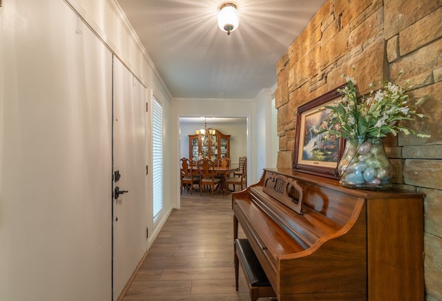 corridor featuring plenty of natural light, wood finished floors, a chandelier, and ornamental molding