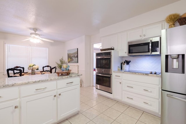 kitchen featuring ceiling fan, appliances with stainless steel finishes, white cabinetry, and light tile patterned floors