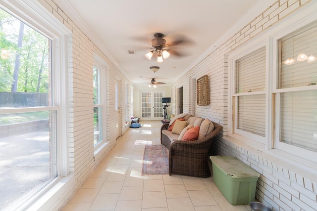 sunroom with plenty of natural light, a ceiling fan, and french doors