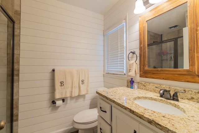 bathroom featuring wooden walls, a shower stall, toilet, and vanity