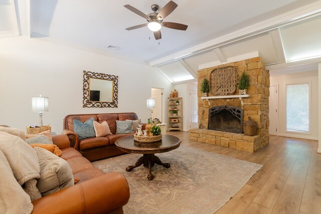 living area with vaulted ceiling with beams, visible vents, light wood-style floors, a ceiling fan, and a fireplace