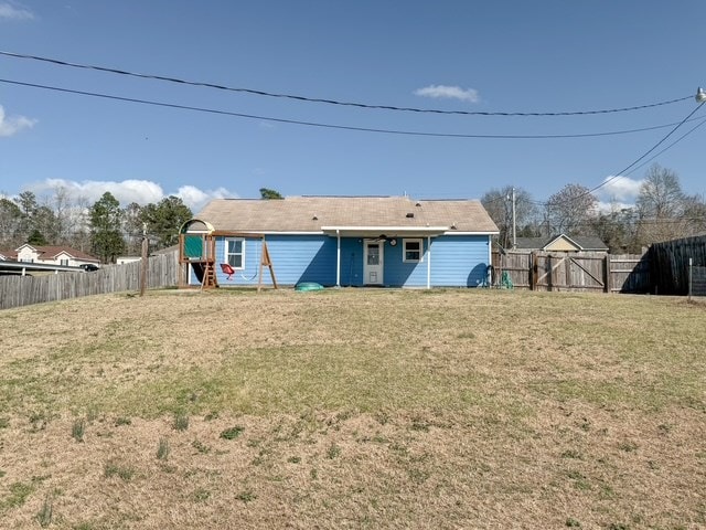 rear view of property with a fenced backyard and a yard