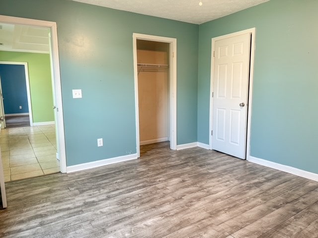 unfurnished bedroom featuring a closet, baseboards, and wood finished floors