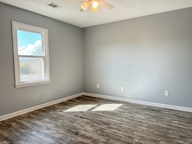 empty room with a ceiling fan, baseboards, visible vents, and dark wood-style flooring