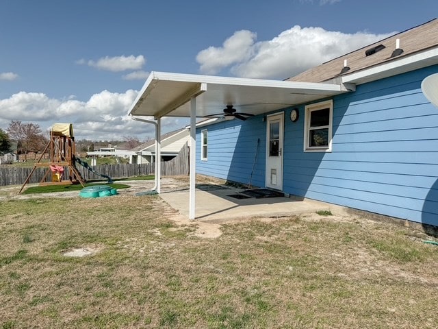 exterior space featuring a ceiling fan, a patio, a playground, fence, and a carport