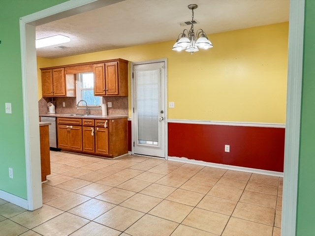 kitchen with visible vents, a sink, light countertops, stainless steel dishwasher, and brown cabinets