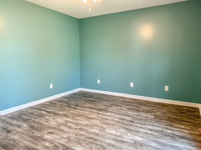 spare room with baseboards, a textured ceiling, and wood finished floors