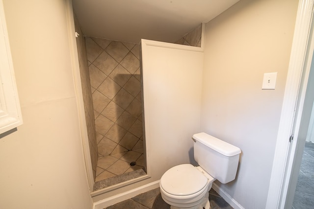 bathroom with a tile shower and toilet