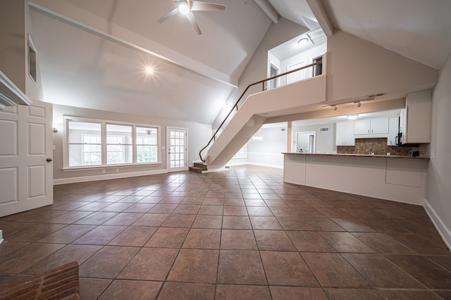 unfurnished living room featuring dark tile patterned floors, ceiling fan, high vaulted ceiling, and beam ceiling