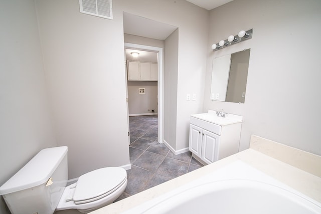 bathroom featuring vanity, a tub to relax in, and toilet