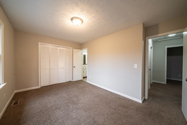 unfurnished bedroom with dark colored carpet, a textured ceiling, and a closet