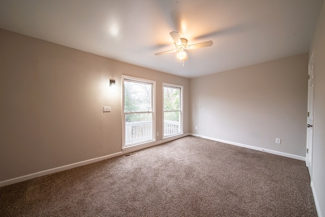 unfurnished room with ceiling fan and dark carpet