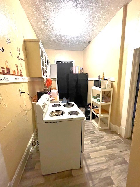 kitchen with light wood-style flooring, freestanding refrigerator, electric range, and a textured ceiling