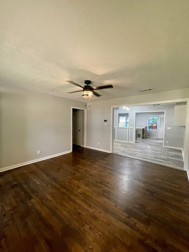 unfurnished living room with a textured ceiling, dark hardwood / wood-style flooring, and ceiling fan