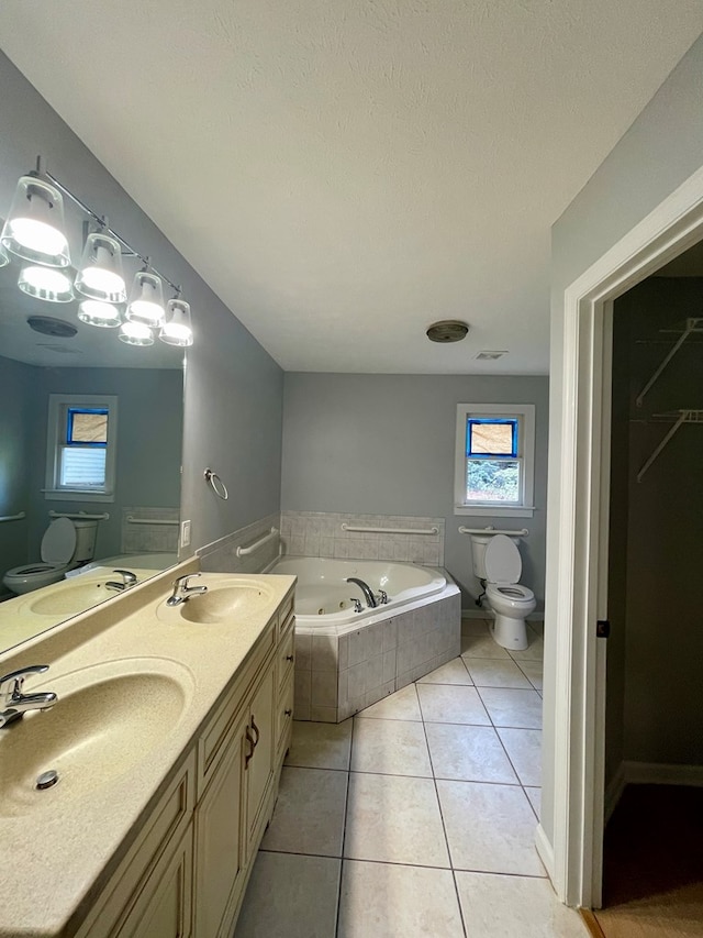 bathroom featuring vanity, tile patterned floors, toilet, a textured ceiling, and tiled tub