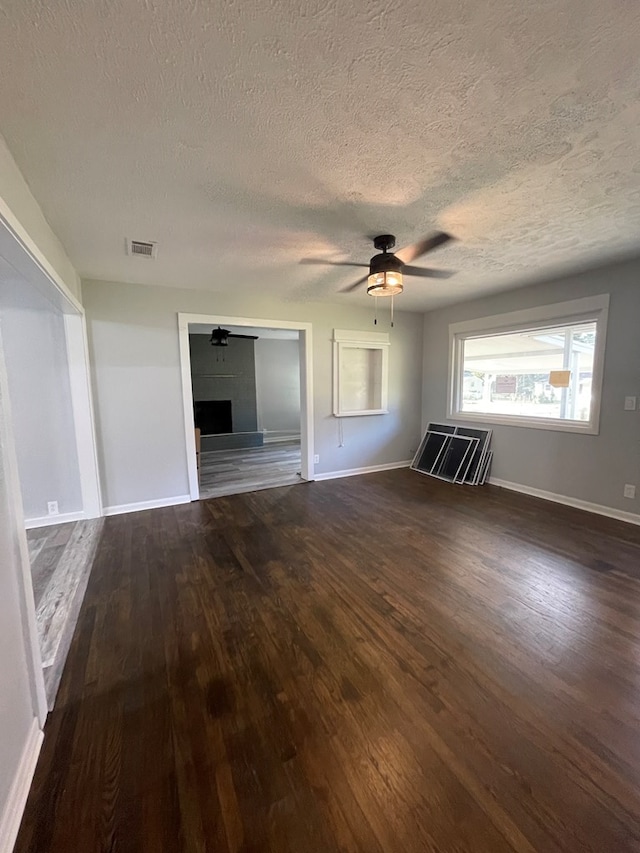 unfurnished living room featuring a textured ceiling, ceiling fan, and dark wood-type flooring