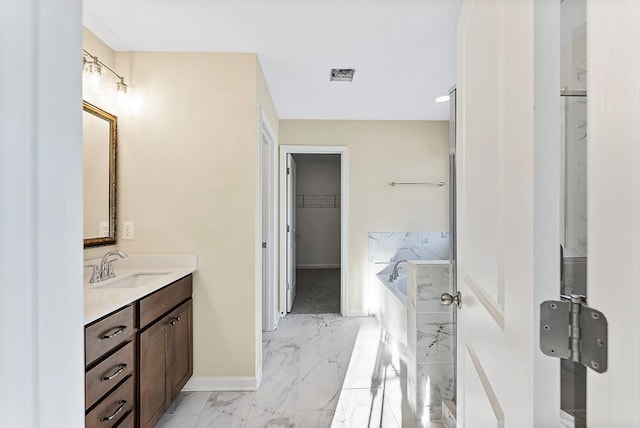 full bath featuring a spacious closet, visible vents, baseboards, marble finish floor, and vanity