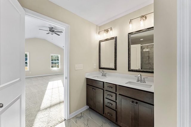 full bath featuring double vanity, baseboards, lofted ceiling, and a sink