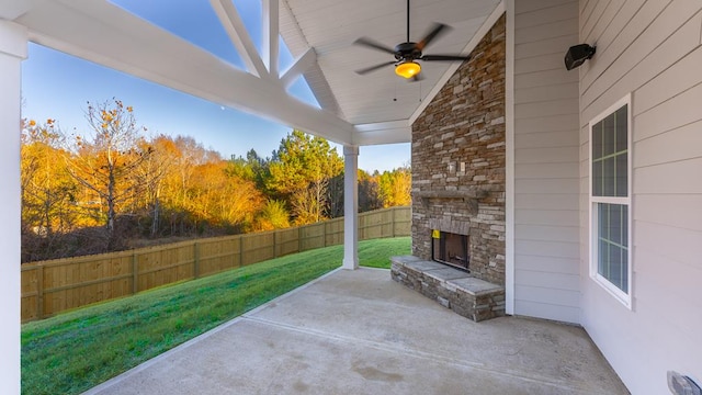 view of patio featuring ceiling fan, an outdoor stone fireplace, and a fenced backyard