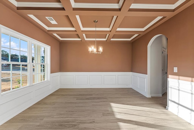 empty room featuring visible vents, light wood finished floors, beam ceiling, arched walkways, and a notable chandelier