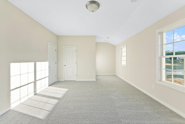 empty room with baseboards, light carpet, and lofted ceiling