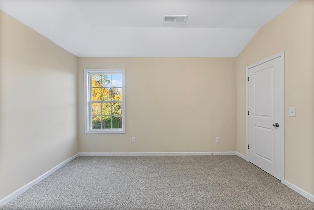 carpeted spare room featuring visible vents, baseboards, and vaulted ceiling