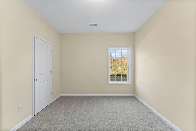 empty room with carpet, visible vents, and baseboards