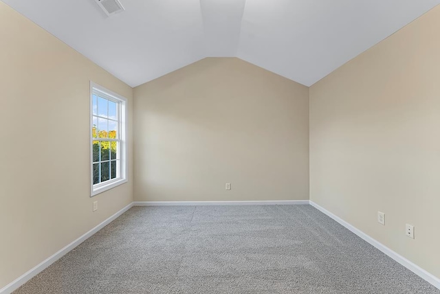 spare room featuring visible vents, carpet flooring, baseboards, and vaulted ceiling