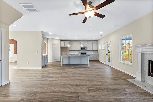 kitchen with visible vents, a ceiling fan, tasteful backsplash, a high end fireplace, and appliances with stainless steel finishes