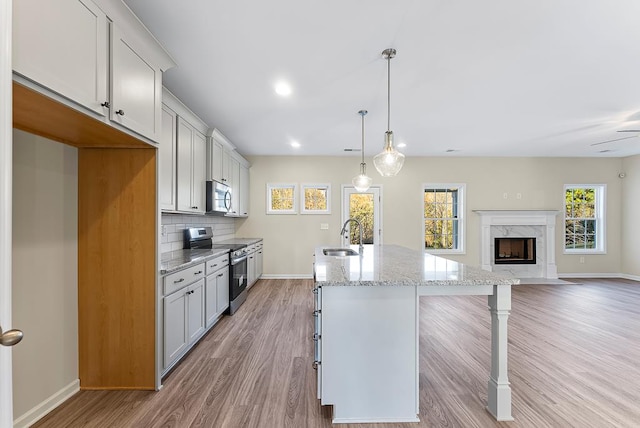 kitchen featuring a center island with sink, a sink, stainless steel appliances, a kitchen bar, and tasteful backsplash