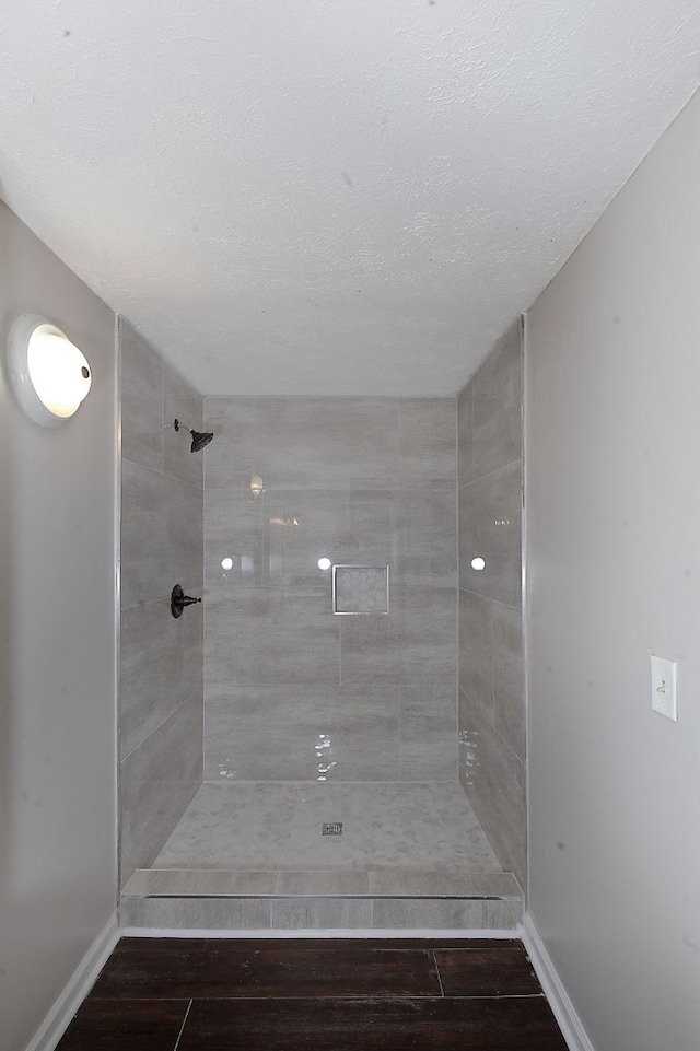 bathroom featuring a tile shower and a textured ceiling