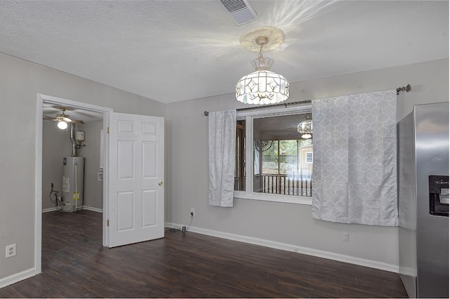 unfurnished room featuring ceiling fan with notable chandelier, a textured ceiling, dark wood-type flooring, and water heater