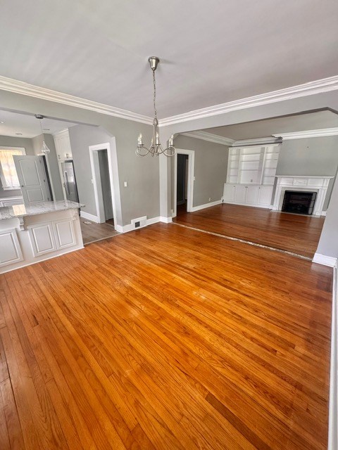1616 Crest Dr, Columbus, GA 31906 - unfurnished living room with light wood-style flooring, a fireplace, a chandelier, and crown molding
