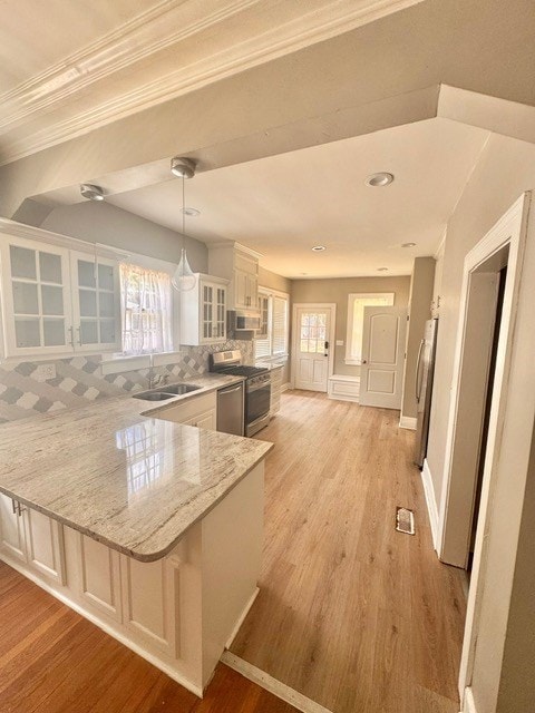 1616 Crest Dr, Columbus, GA 31906 - kitchen featuring stainless steel appliances, ornamental molding, a peninsula, glass insert cabinets, and light wood finished floors
