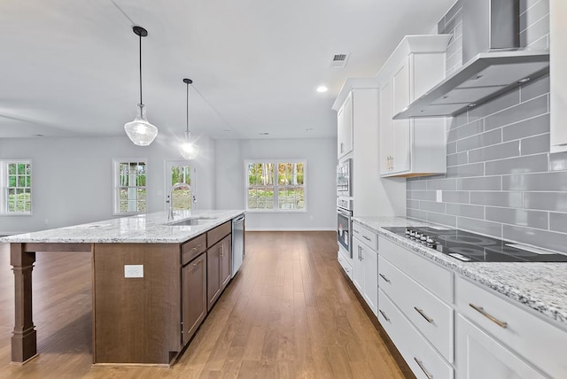 33 Oak Ridge Dr, Waverly Hall, GA 31831 - kitchen featuring an island with sink, wood finished floors, a sink, wall chimney exhaust hood, and appliances with stainless steel finishes