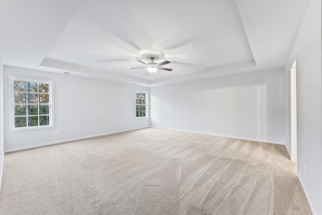 carpeted spare room featuring ceiling fan and a raised ceiling