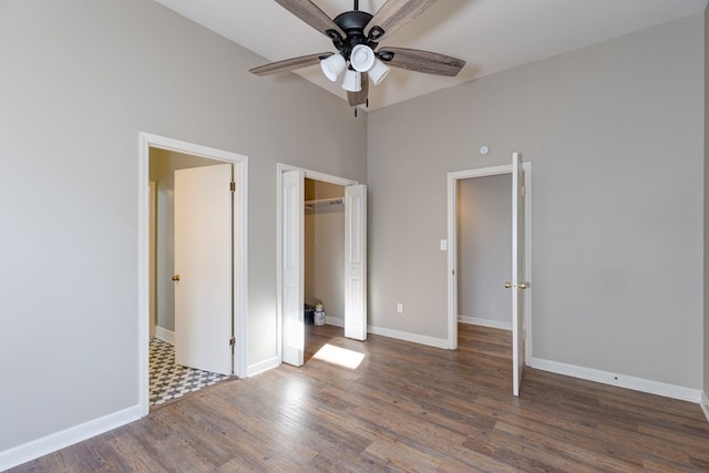 unfurnished bedroom with ceiling fan, a high ceiling, dark hardwood / wood-style flooring, and a closet