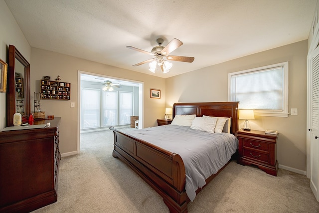 bedroom with a ceiling fan, light colored carpet, and baseboards