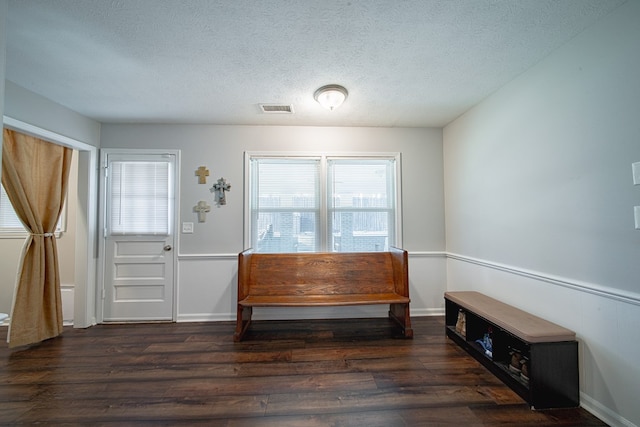 foyer featuring visible vents, baseboards, a textured ceiling, and wood finished floors